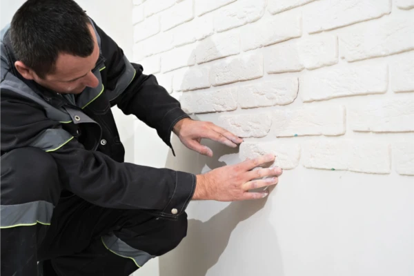 Werker pleister werken aan het doen op een witte muur